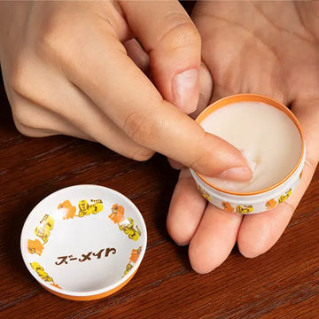 アデリアレトロ フレグランスマルチバーム ズーメイトの使用画像。缶の蓋が開いていて、人差し指でバームをすくっている。